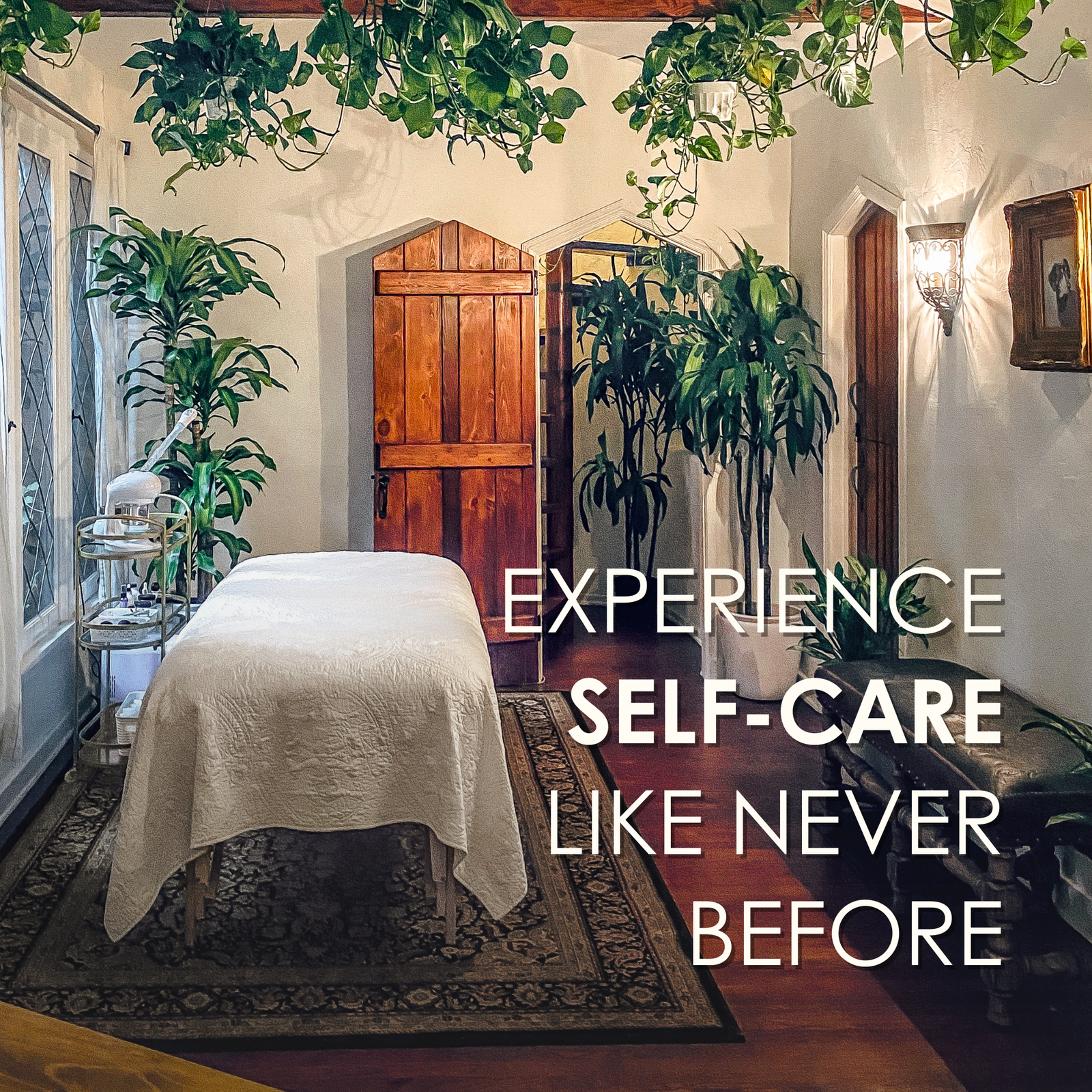 Flora Mirabilis treatment room featuring a massage table, plants, and soft lighting with text overlay reading ‘Experience self-care like never before.’