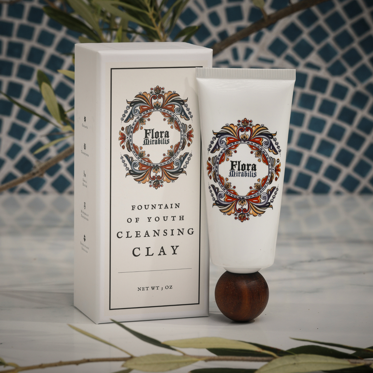 Flora Mirabilis Fountain of Youth Cleansing Clay tube displayed beside its packaging on a marble surface with mosaic tile background.