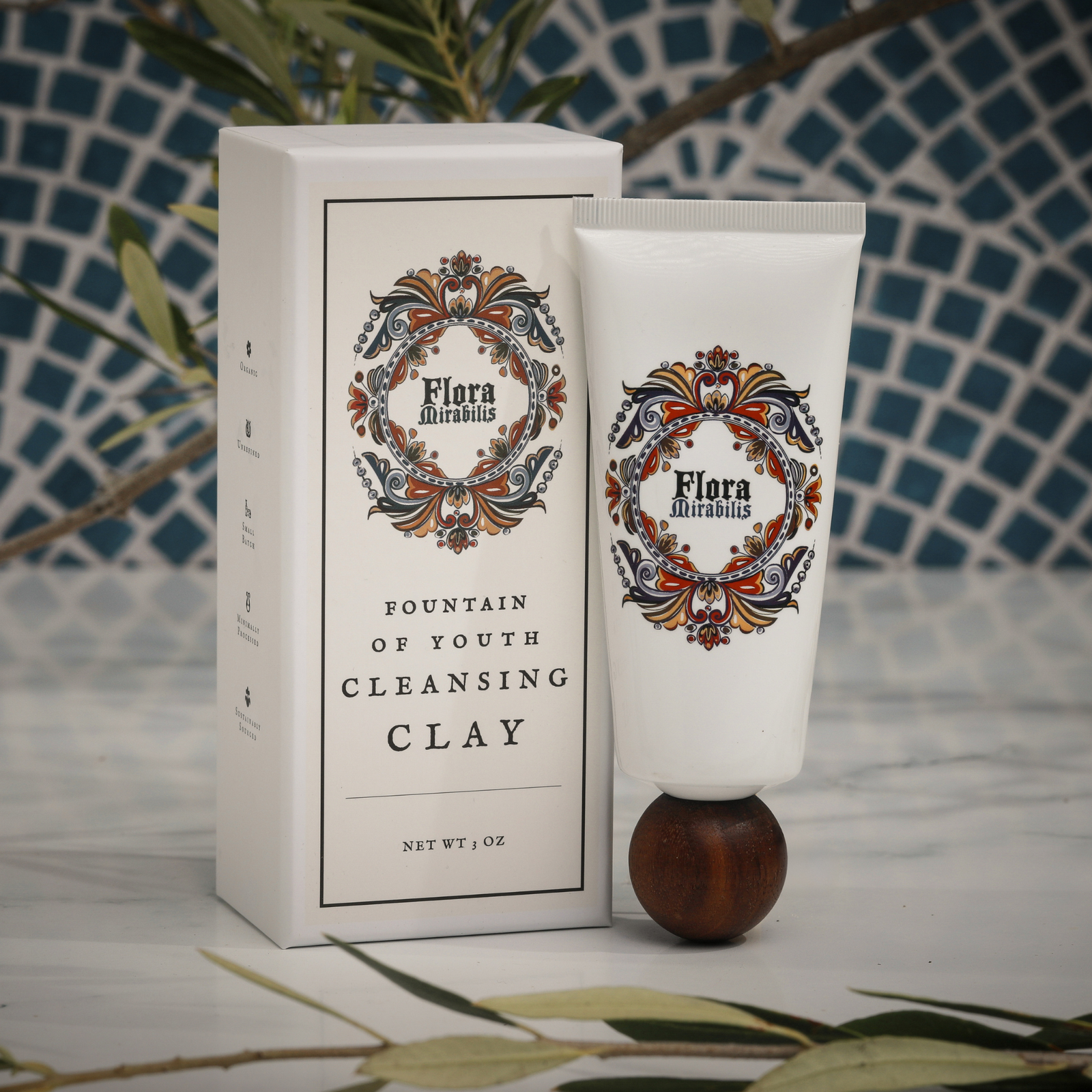Flora Mirabilis Fountain of Youth Cleansing Clay tube displayed beside its packaging on a marble surface with mosaic tile background.