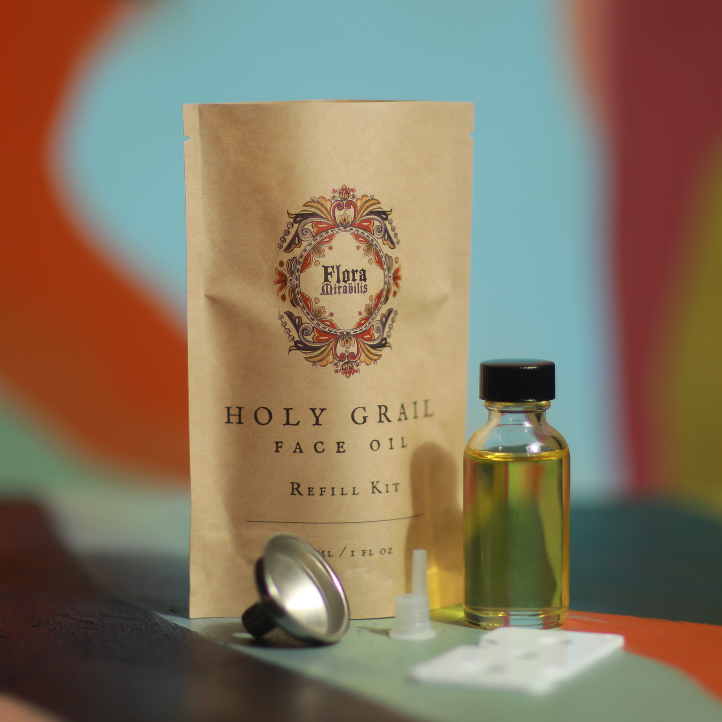 Flora Mirabilis Holy Grail Face Oil refill kit with oil bottle and packaging on a colorful background