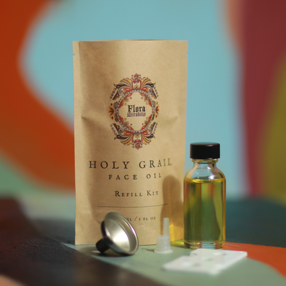 Flora Mirabilis Holy Grail Face Oil refill kit with oil bottle and packaging on a colorful background