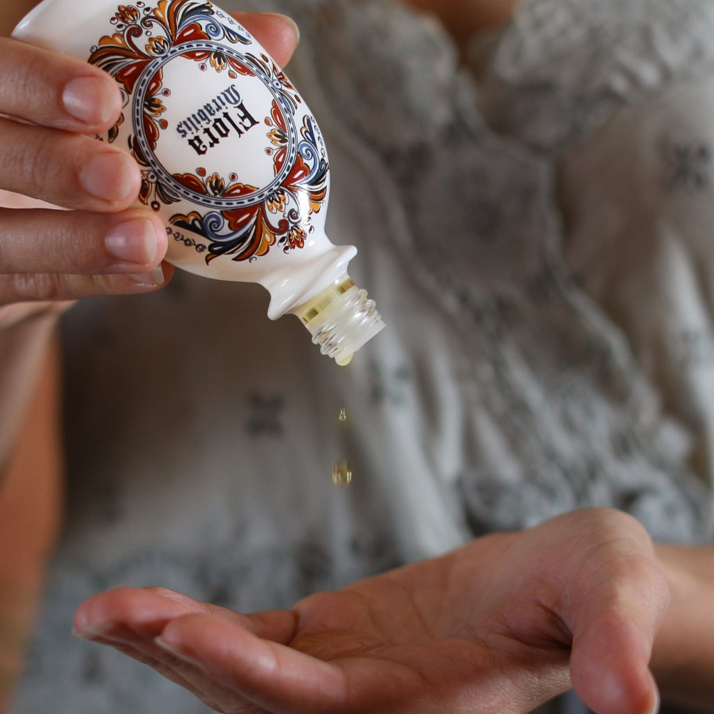 Jordan LaFagola holding a Holy Grail Face Oil bottle and dispensing a couple drops into her hand.