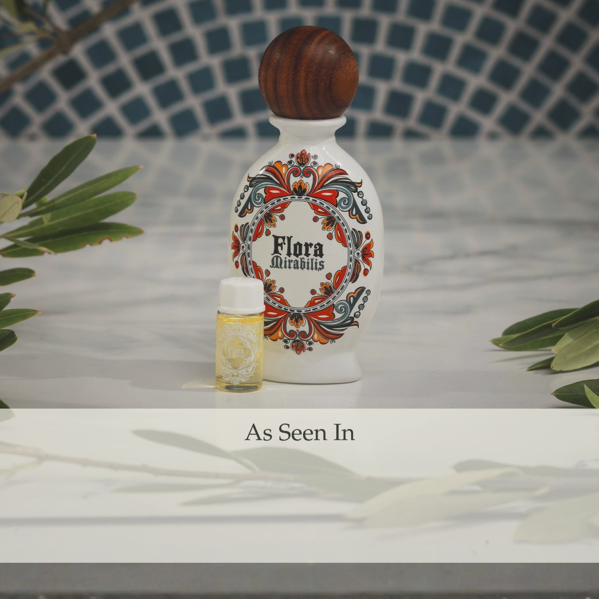 Flora Mirabilis Holy Grail Face Oil full-size bottle and trial vial displayed together with an ‘As Seen In’ press mention banner on a marble surface. Featured in GLAMOUR, Town & Country, Forbes, Byrdie, L'OFFICIEL, Santa Barbara Magazine, and Bustle.